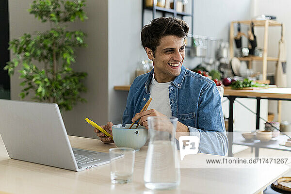 Happy man with smart phone and laptop at table
