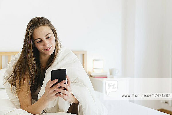 Smiling young woman with brown hair using smart n bed