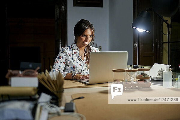 Businesswoman working on laptop in office at night