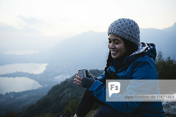 Smiling woman with eyes closed holding coffee mug on mountain