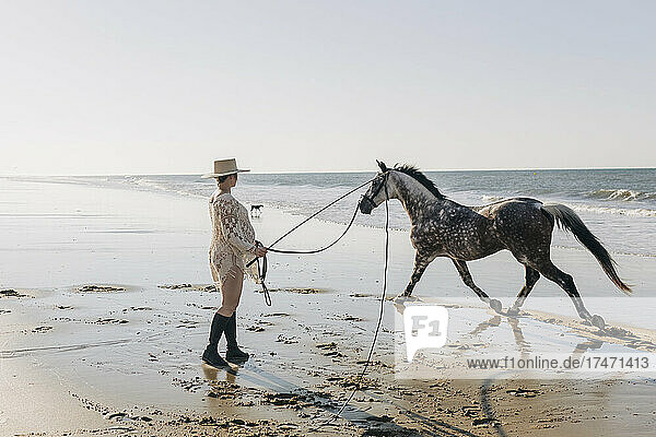 Pregnant woman with horse on wet beach