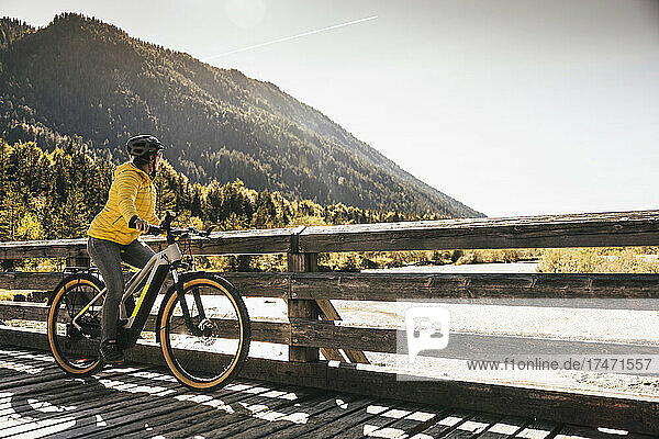 Woman with bicycle looking at mountain on sunny day