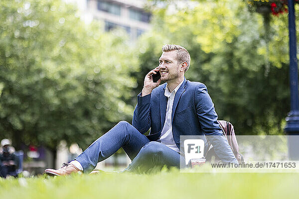 Smiling male professional talking on smart phone in park