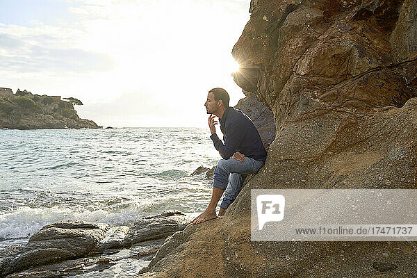 Man leaning on rock formation at beach
