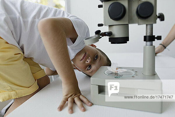 Junge blickt auf Mikroskop auf Tisch