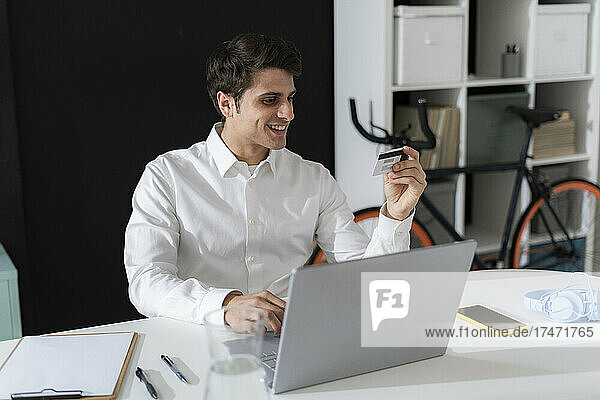 Smiling businessman doing online shopping through laptop at office