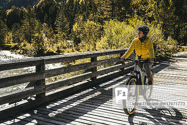 Mature woman riding mountain bike on bridge
