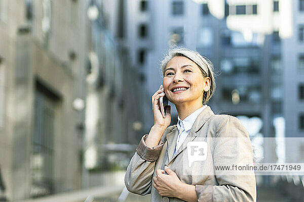 Smiling woman talking on smart phone in city
