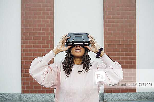 Junge Frau benutzt Virtual-Reality-Simulator vor der Wand