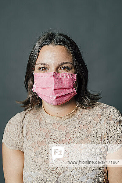 Woman in pink protective face mask against gray background