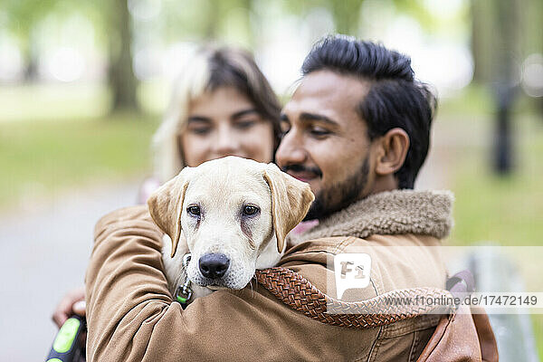 Smiling young man carrying dog in public park