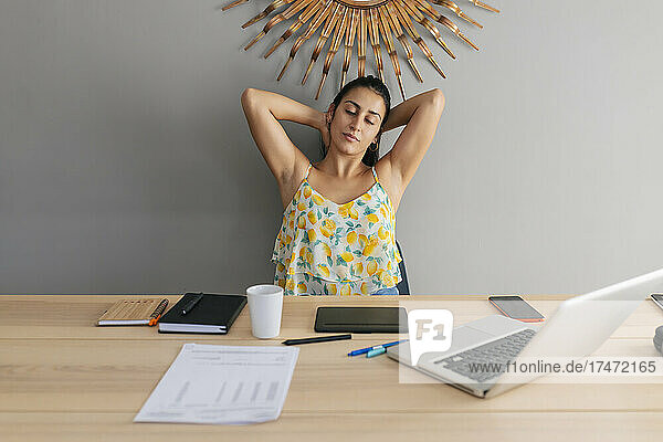 Working woman with arms raised relaxing at home