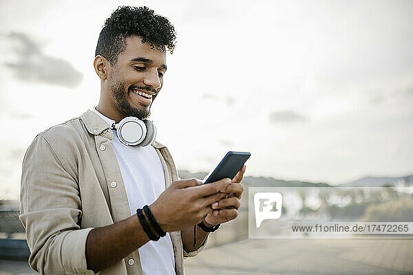 Happy man with wireless headphones using smart phone