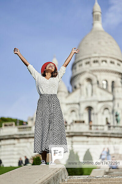 Carefree woman with hands raised standing on steps