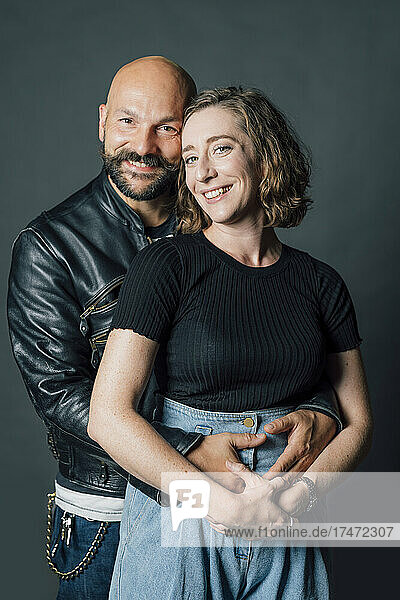 Mid adult couple embracing against gray background