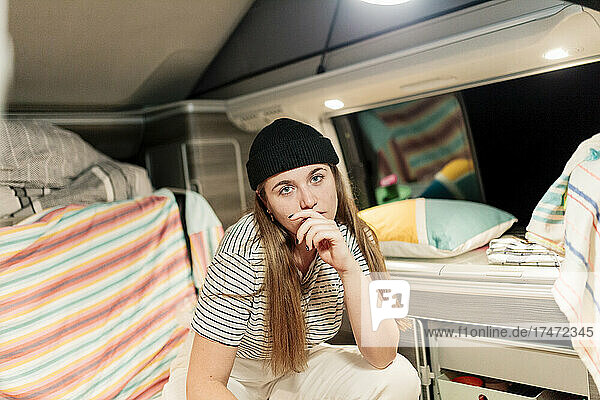 Young woman wearing knit hat sitting in camper van