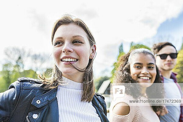 Young woman looking away with friends in park