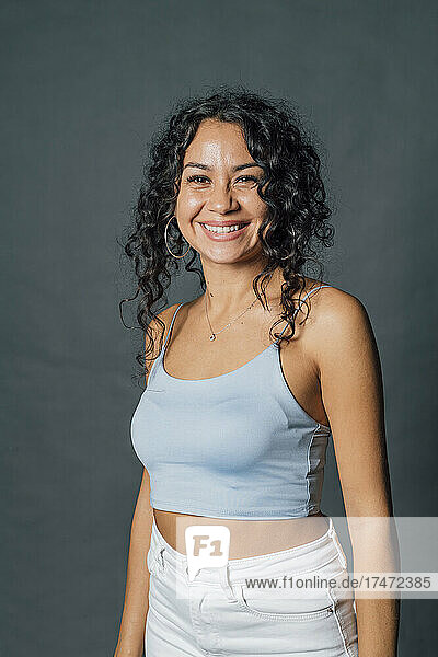 Woman in casuals smiling against gray background