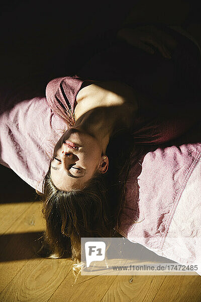 Lonely young woman with eyes closed lying on bed at home