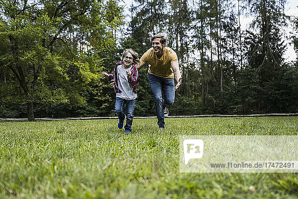 Playful son and father running on grass at park