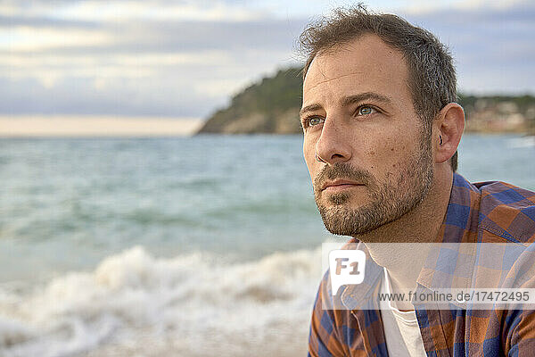 Thoughtful man spending sunset at beach