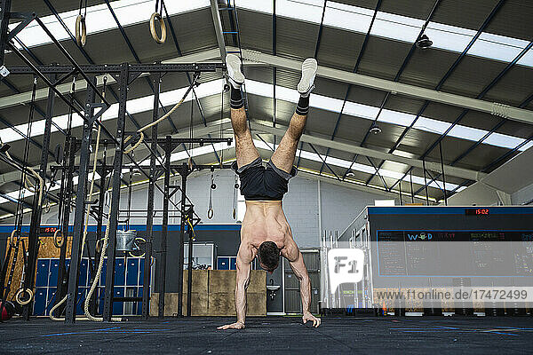 Young male athlete doing handstand in gym