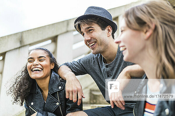 Young man with hat leaning on cheerful friends