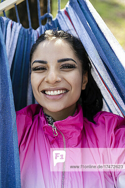 Happy woman lying in hammock at park