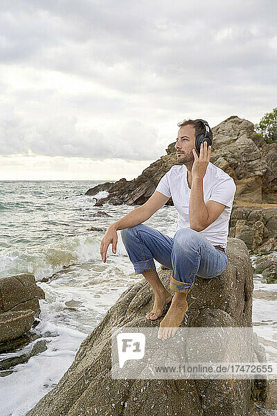 Man listening music on headphones at beach