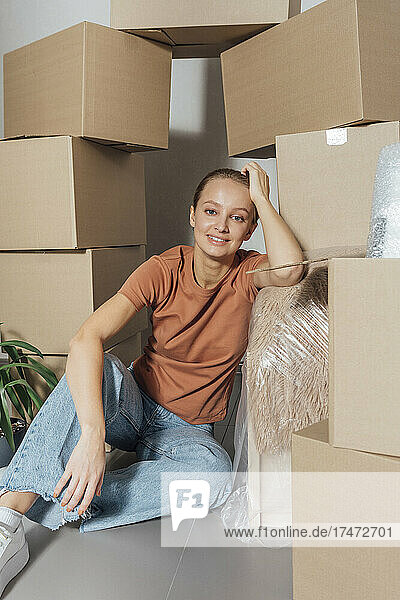 Young woman leaning by cartons at new home