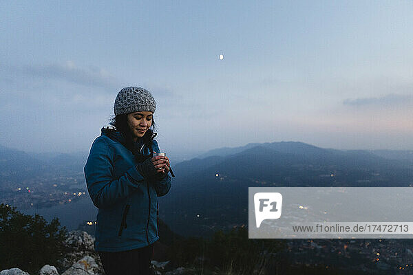 Hiker looking at coffee mug on mountain