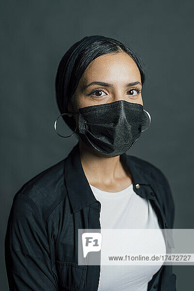 Woman wearing black protective face mask against gray background