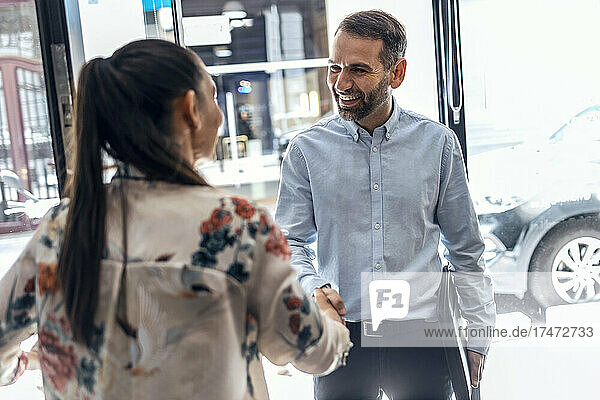 Smiling businessman greeting businesswoman in office