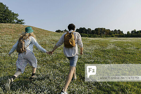 Man holding hand of girlfriend running on meadow