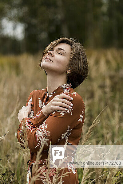 Woman with eyes closed hugging herself