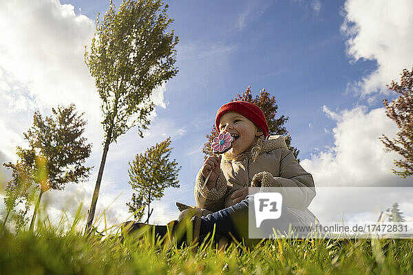 Mädchen isst Süßigkeiten  während es im Park sitzt