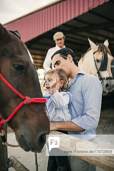 Vater und Tochter betrachten Pferd im Stall