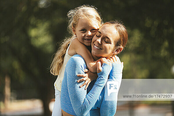 Happy mother giving piggyback to daughter at park