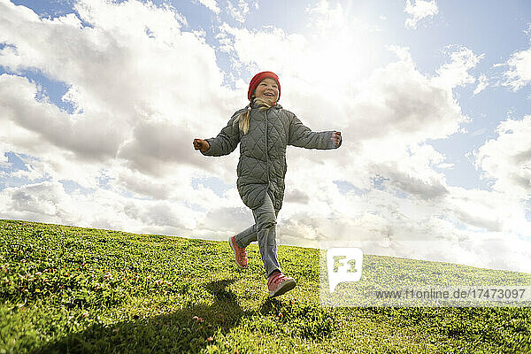 Carefree girl running on grass during sunny day