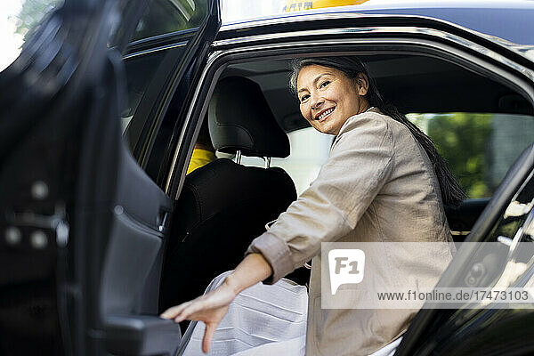 Lächelnde Frau schließt Taxitür