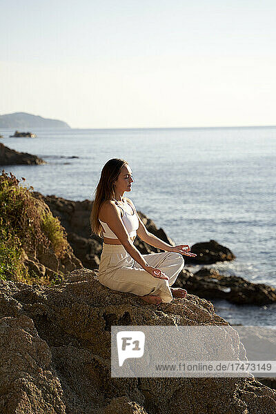 Female athlete practicing lotus position on rock