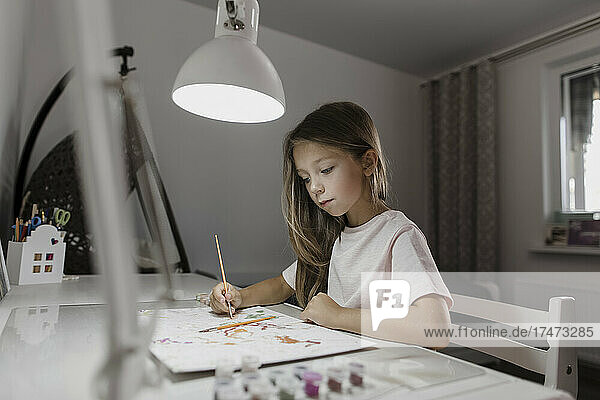 Mädchen malt am Schreibtisch auf Papier