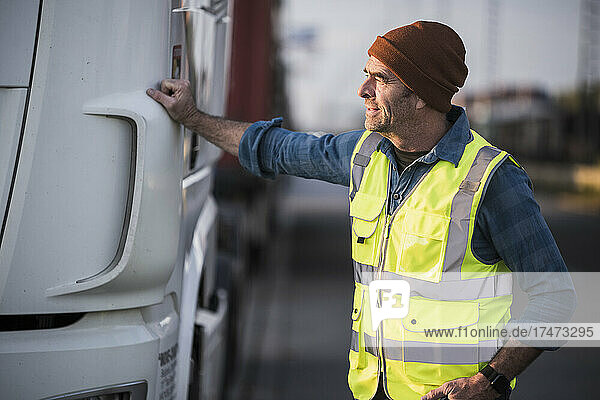 Male driver standing by truck at commercial dock