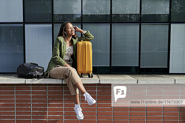 Woman with eyes closed leaning on wheeled luggage