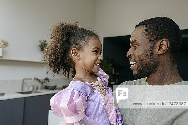 Happy man looking at daughter in kitchen