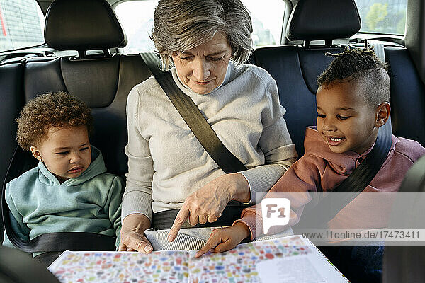 Grandmother reading book with grandchildren in car