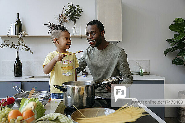Lächelnder Junge zeigt seinem Vater in der Küche Spaghetti