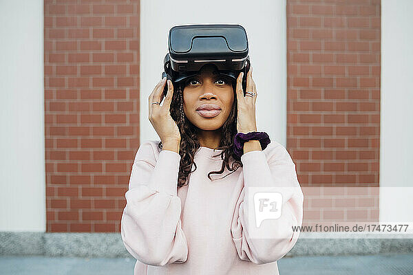 Woman holding virtual reality headset in front of wall
