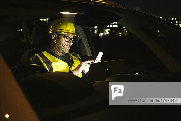 Engineer with hardhat using mobile phone in car