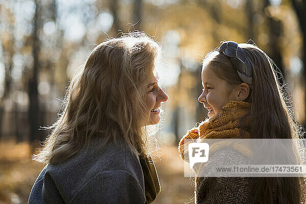 Blond woman smiling at daughter in public park